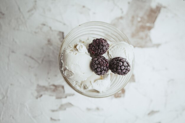 Brombeeren in einer Glasschale mit Eiscreme Draufsicht auf einem weißen strukturierten