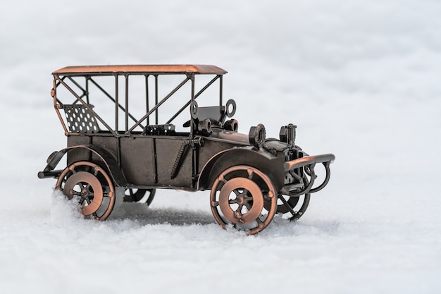 Bronze-Modell-Spielzeug-Retro-Auto steht auf weißem Schnee