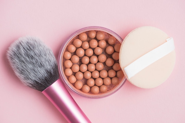 Bronzing Perlen; Schwamm und Make-up Pinsel auf rosa Hintergrund