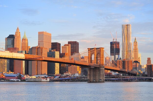 Brooklyn Bridge mit Skyline von Lower Manhattan am Morgen mit bunten Wolken über dem East River in New York City