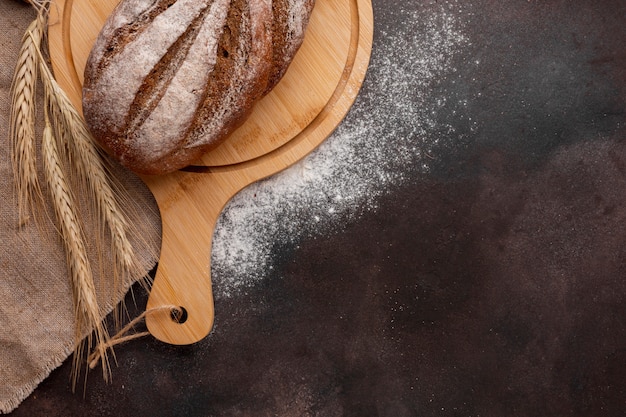 Brot auf Holzbrett mit Weizengras und Mehl