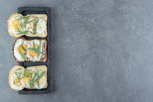 Brot mit gekochten Eiern auf schwarzem Teller.