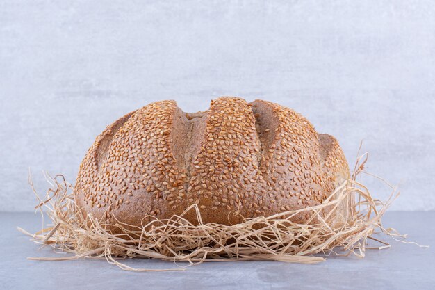 Brot sitzt auf einem Strohhaufen auf Marmoroberfläche