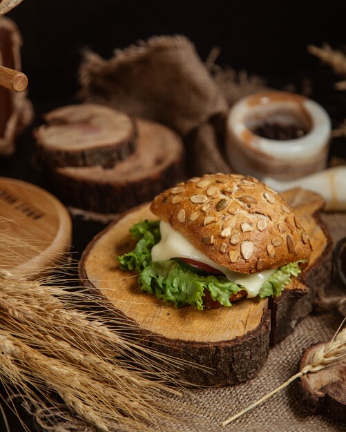 Brotsandwich mit geschmolzenem Käse und Kopfsalat auf einem Stück Holz.