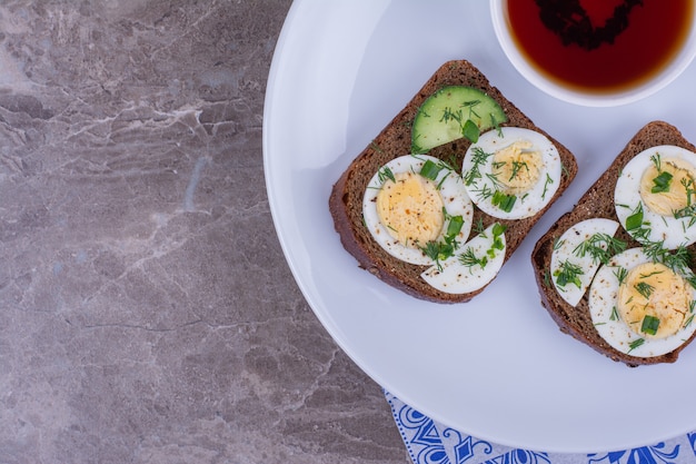 Brotscheiben mit Ei und Kräutern, serviert mit einer Tasse Tee