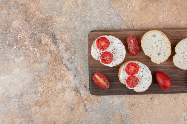 Brotscheiben mit Sahne und Tomate auf Holzbrett