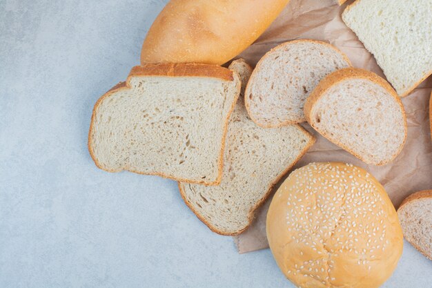 Brotscheiben und Brötchen mit Sesam auf blauem Hintergrund. Hochwertiges Foto