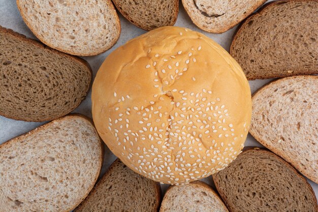 Brotscheiben und Brötchen mit Sesam auf blauem Hintergrund. Hochwertiges Foto