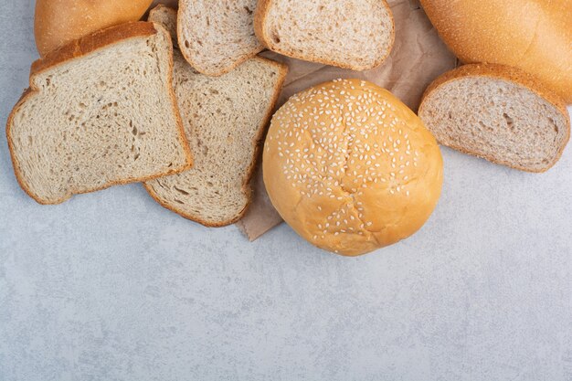 Brotscheiben und Brötchen mit Sesam auf Papierblatt. Hochwertiges Foto