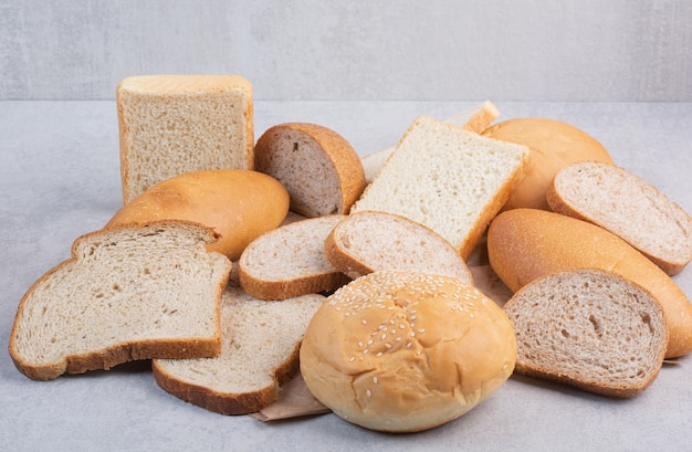 Brotscheiben und Brötchen mit Sesam auf Papierblatt