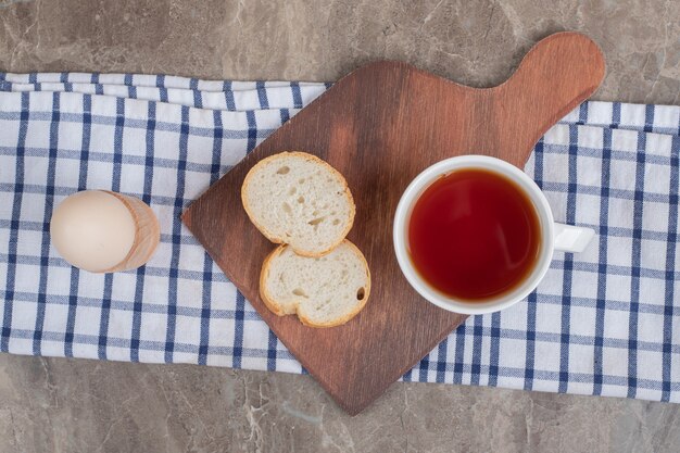 Brotscheiben und eine Tasse Tee auf Holzbrett mit Ei. Hochwertiges Foto