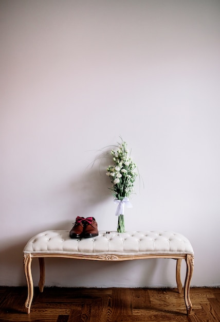 Brown-Schuhe und Hochzeitsblumenstrauß stehen auf einem Sofa