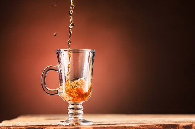 Brown spritzt Getränk aus Tasse Tee auf einem braunen Hintergrund aus