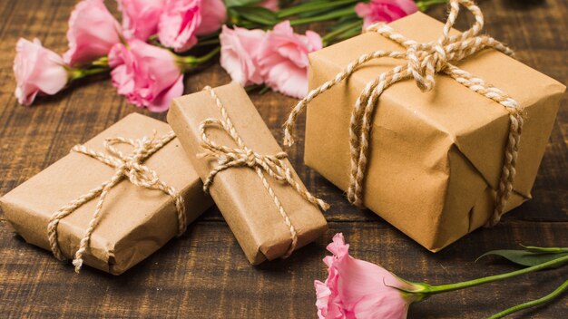Brown wickelte Geschenkboxen und rosa Eustoma-Blumen auf Holzoberfläche ein