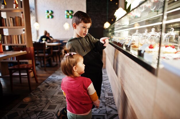 Bruder mit Schwester im Café wählen Sie ein Dessert aus dem Schaufenster