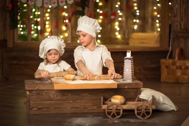 Bruder und Schwester gebacken den Teig ist ausgerollt das Konzept der kleinen Helfer der Mutter