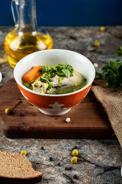 Brühe Suppe mit Kräutern, Kartoffeln und Karotten in einer roten Schüssel