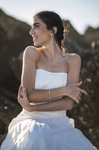 Brünette Frau in einem weißen Kleid mit einem aufrichtigen Lächeln