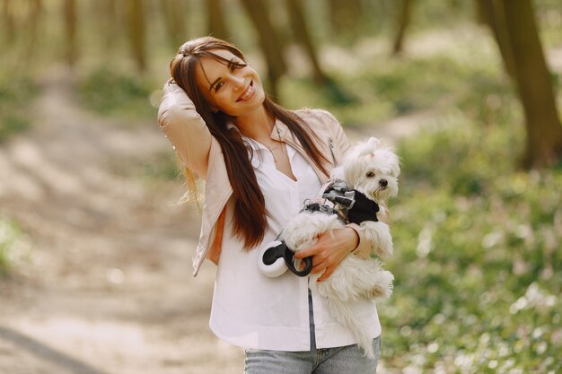 Brünette in einem Wald geht mit niedlichem Hund