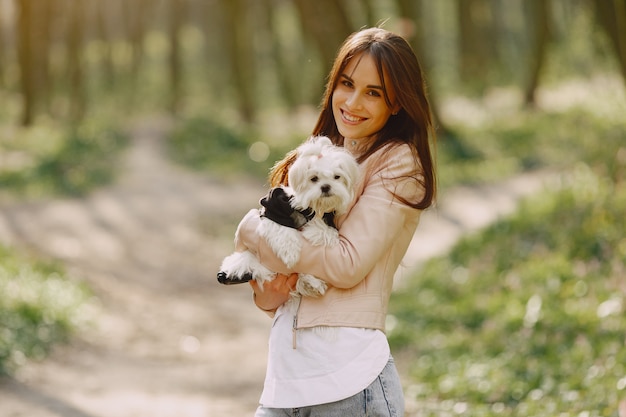 Brünette in einem Wald geht mit niedlichem Hund