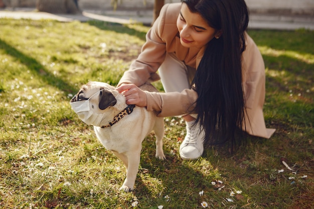 Brünette in einer Maske geht mit Mops