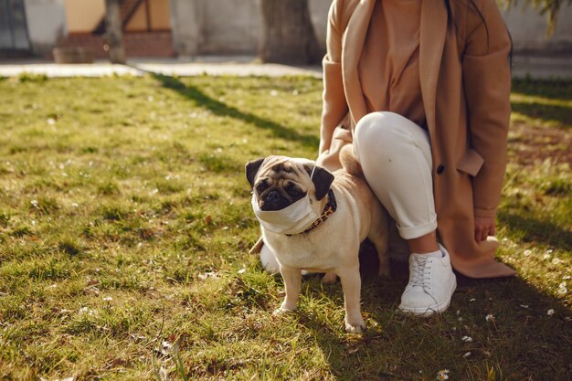 Brünette in einer Maske geht mit Mops