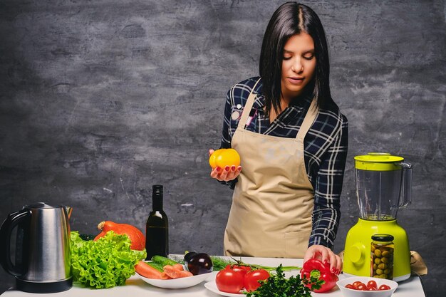 Brünette Köchin am Tisch bereitet vegane Mahlzeiten zu.