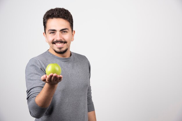 Brünetter Mann, der grünen Apfel glücklich hält.