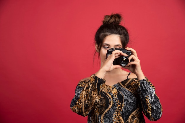 Brünettes Mädchen, das eine professionelle DSLR-Kamera hält und Fotosession macht.