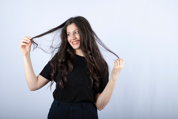 brünettes Mädchen im schwarzen Oberteil, das mit Haaren spielt.