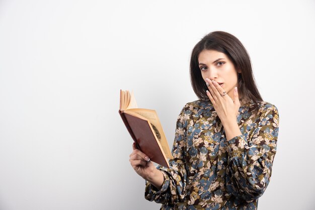 Brunette Frau, die Buch auf einem weißen Hintergrund liest.