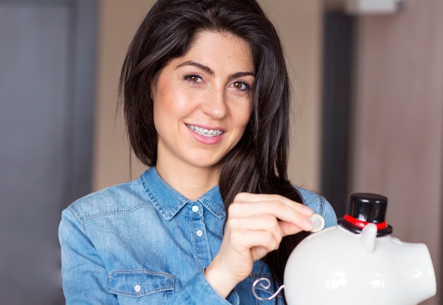 Brunette Frau, eine Münze in die Sparschwein