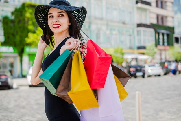 Brunette Mädchen stand auf der Straße halten Taschen