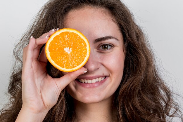 Brunettefrau, die eine Orange anhält