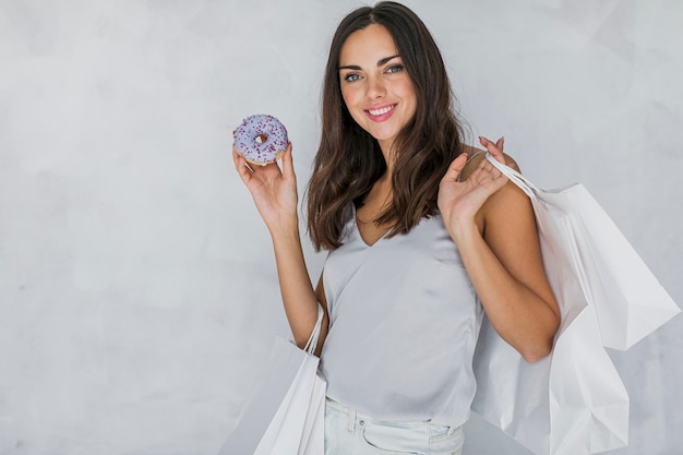 Brunettefrau mit einem Donut und Einkaufsnetzen