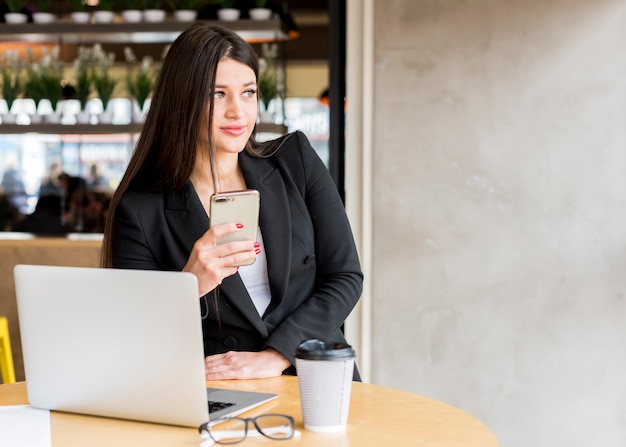 Brunettegeschäftsfrau, die ihren Smartphone verwendet