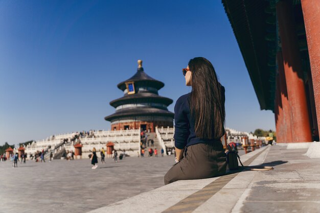 Brunettemädchen, das auf den Schritten durch Tempel von Heven in China sitzt