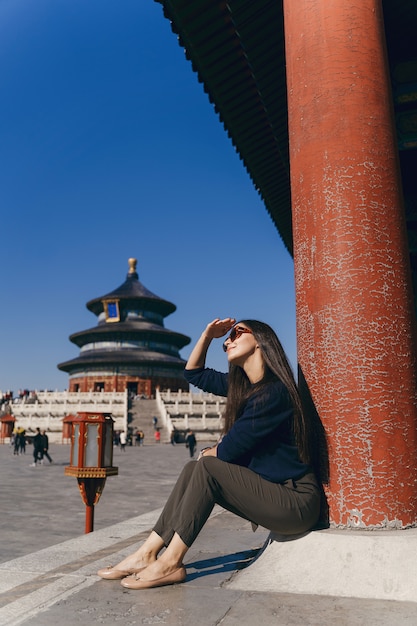 Brunettemädchen, das auf den Schritten durch Tempel von Heven in China sitzt