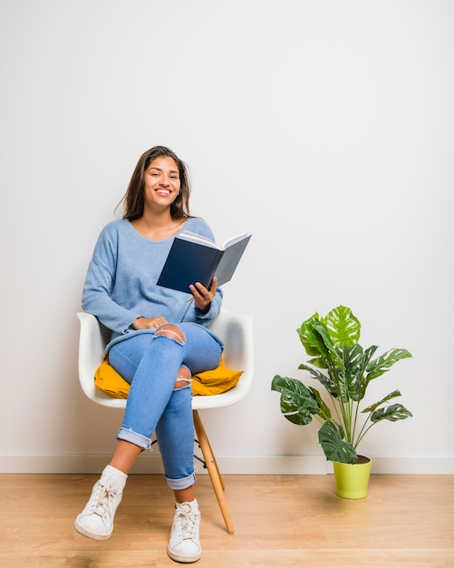 Brunettemädchen, das ein Buch lesend sitzt