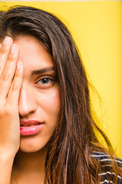 Brunettemädchen mit der Hand auf dem Gesicht