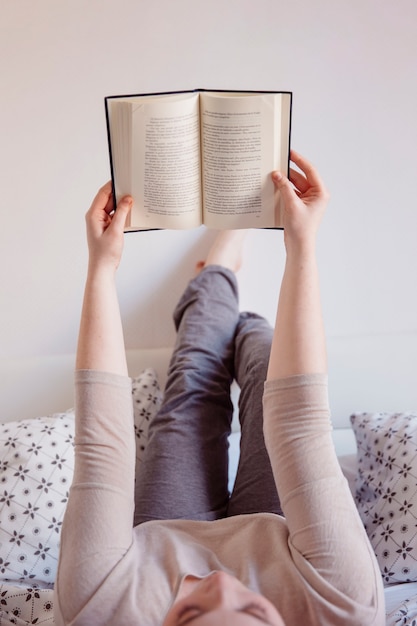 Kostenloses Foto buch der jungen frau leseim bett