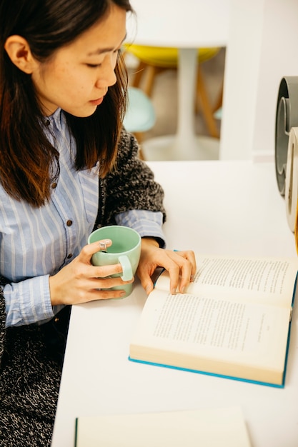 Buch des jungen Mädchens Leseund trinkender Kaffee