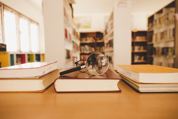 Kostenloses Foto buch in bibliothek mit alten offenen lehrbuch, stapel von literatur-text-archiv auf leseschreibtisch