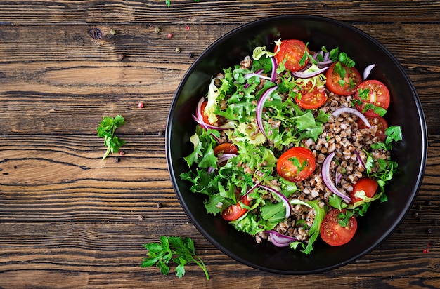 Buchweizensalat mit Kirschtomaten, roten Zwiebeln und frischen Kräutern. Veganes Essen. Diät-Menü. Ansicht von oben. Flach liegen