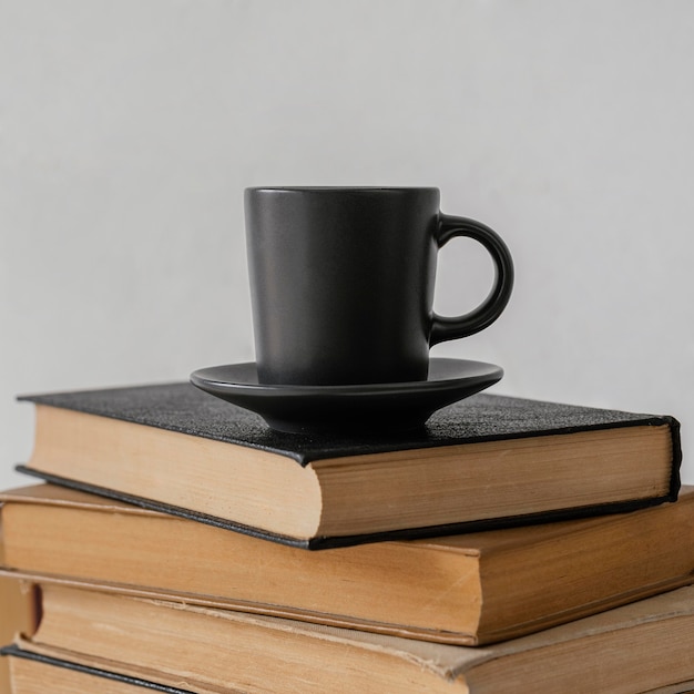 Bücher stapeln sich drinnen und Kaffeetasse