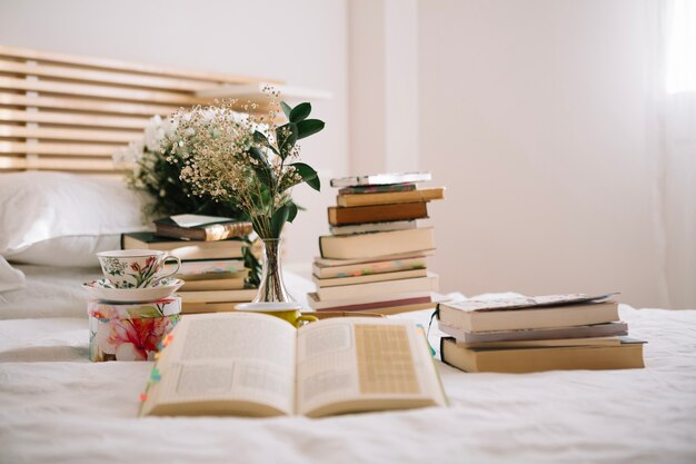 Bücher und Blumenstrauß auf dem Bett am Morgen