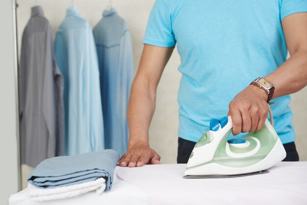 Bügelnde Hemden und Wäscherei des unerkennbaren Mannes zu Hause