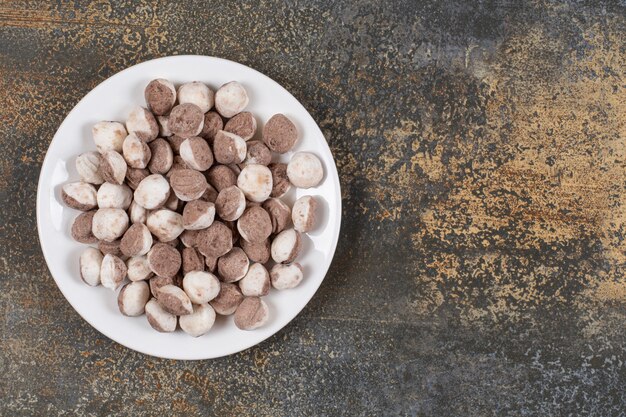 Bündel braune Bonbons auf weißem Teller.