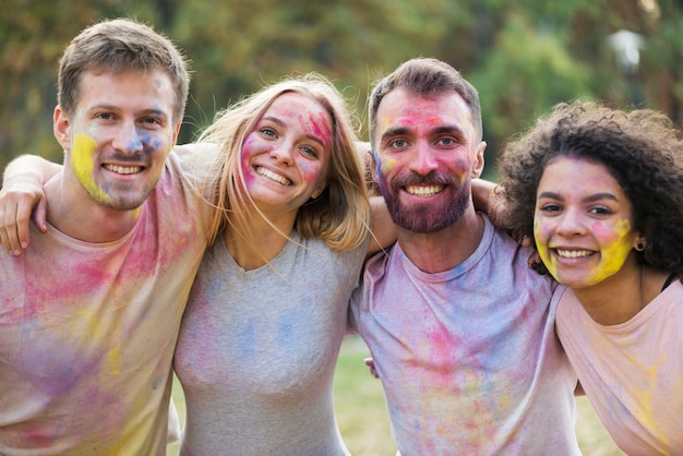 Bündel Freunde, die mit gemalten Gesichtern am Festival lächeln und aufwerfen