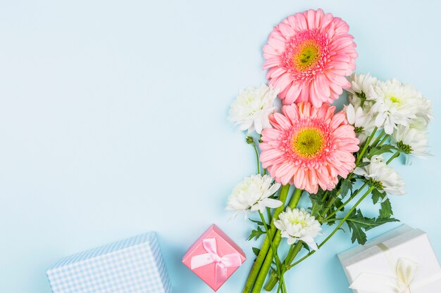 Bündel frische Blumen nahe Geschenkboxen